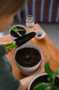 Beyaz tencerelerde çiçek nakleden bir kız.