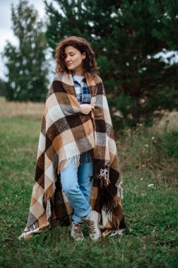 Ormanda ve tarlada kareli bir ekoseye sarılı çekici bir kız.