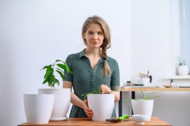 Beyaz tencerelerde çiçek nakleden bir kız.