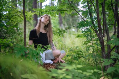 Meditasyon ve doğayla etkileşim pratiği. Yeşil ormandaki kız
