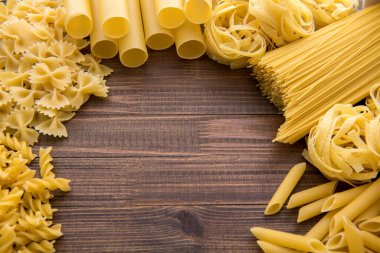 Ahşap arka planda farklı türde makarna. Farfalle, fettuccine, noodle.