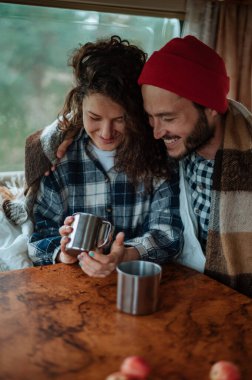 Karavanda bir masada oturan ve çay içen çift..