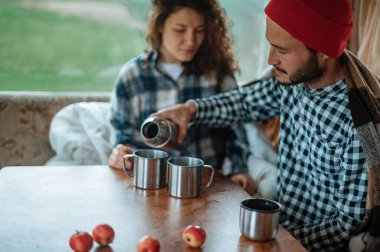 Karavanda bir masada oturan ve çay içen çift..