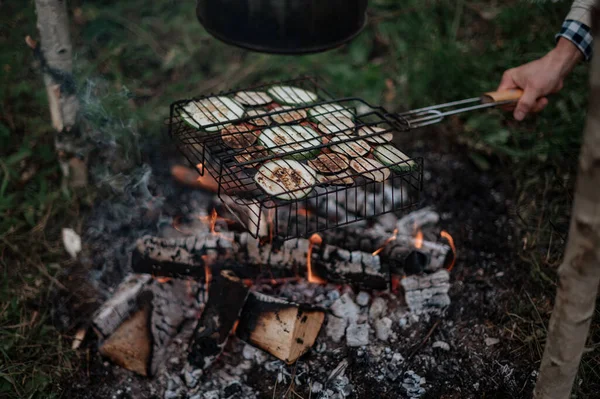 Pár v kostkovaném kostkovaném pečení marshmallows na ohni v blízkosti přívěsu domů. — Stock fotografie