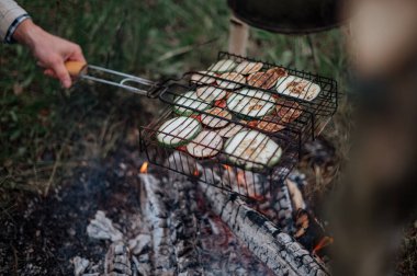 Kareli ekoseli bir çift, karavanın yanında lokum pişiriyor..