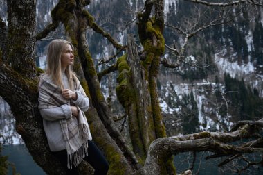 Kız ağaçta oturur ve mavi göl arka planında meditasyon yapar. Abhazya 'daki Ritsa Gölü