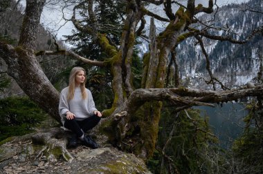 Kız ağaçta oturur ve Abhazya 'da Ritsa Gölü yakınlarında meditasyon yapar.