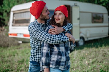 Romantik çift karavanın yanında birlikte vakit geçiriyorlar. Yakışıklı sakallı adam ve güzel kadın birlikte eğleniyorlar. Karavanla birlikte seyahat ediyoruz..