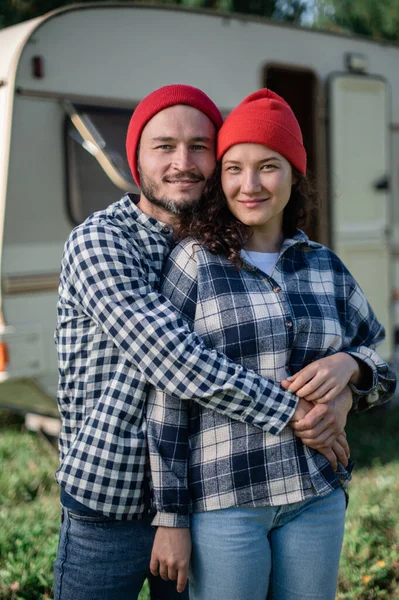 Pareja romántica pasando tiempo juntos cerca de casa remolque. Hombre barbudo guapo y mujer hermosa disfrutando de la compañía de los demás. Viajar juntos con autocaravana. Imagen de stock