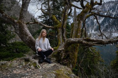 Kız ağaçta oturur ve Abhazya 'da Ritsa Gölü yakınlarında meditasyon yapar.
