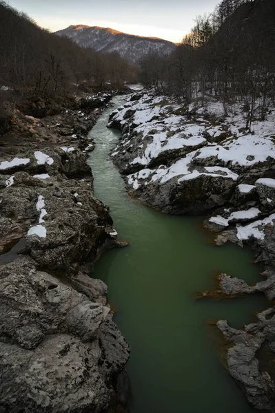 Rio de montanha nevado ao pôr-do-sol. Água de cor verde — Fotografia de Stock