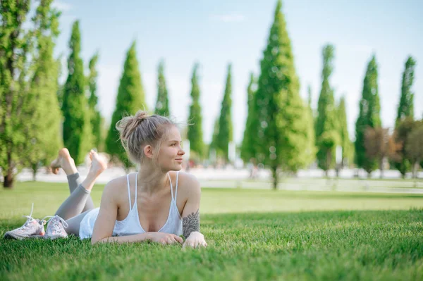 Attraktives sportliches Mädchen liegt auf dem Rasen und entspannt sich im Park — Stockfoto