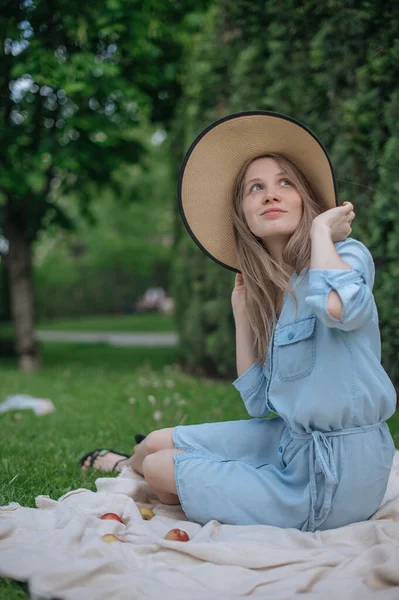 Het meisje droomt van een nieuw appartement. Romantisch meisje met hoed op picknick in park. — Stockfoto