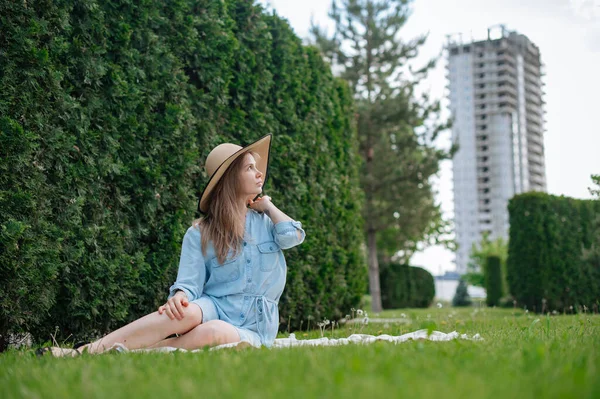 The girl dreams of a new apartment. Romantic girl with hat on picnic in park. — Stock Photo, Image