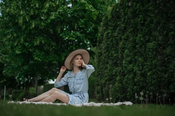 The girl dreams of a new apartment. Romantic girl with hat on picnic in park. — Stock Photo, Image