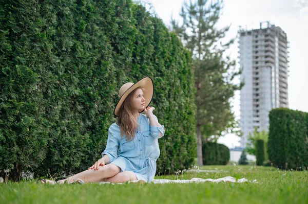 The girl dreams of a new apartment. Romantic girl with hat on picnic in park. — Stock Photo, Image