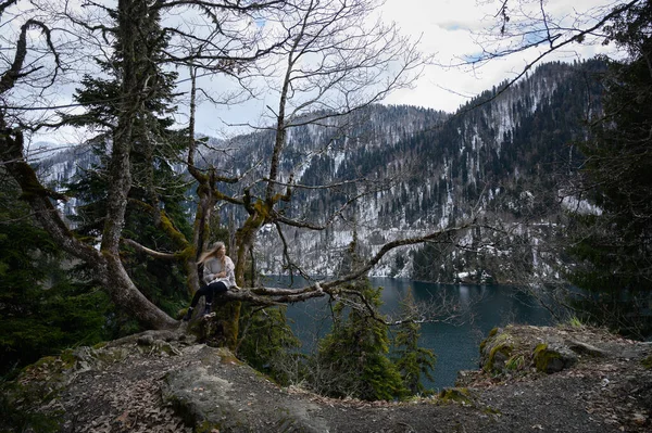 Flicka sitter på ett träd och mediterar nära sjön Ritsa i Abchazien — Stockfoto