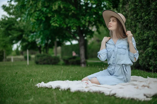 Het meisje droomt van een nieuw appartement. Romantisch meisje met hoed op picknick in park. — Stockfoto