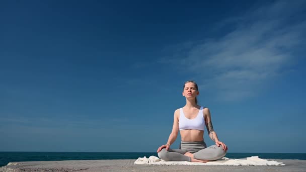 Jóga edzés és meditáció a szabadban. Lány a mólón a tenger hátterében — Stock videók