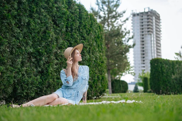The girl dreams of a new apartment. Romantic girl with hat on picnic in park. — Stock Photo, Image