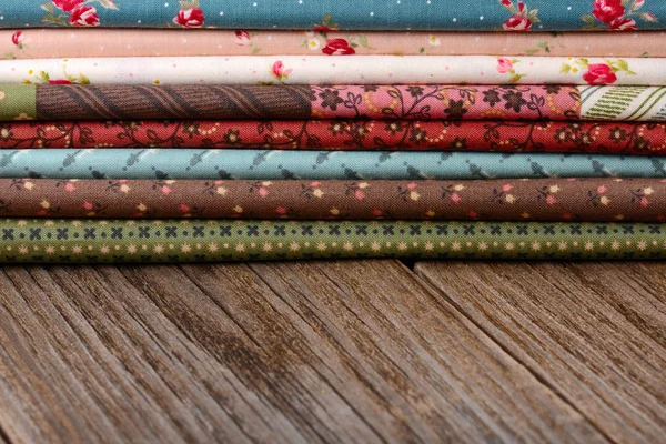 Mucchio di tessuti di stoffa su tavolo di legno — Foto Stock