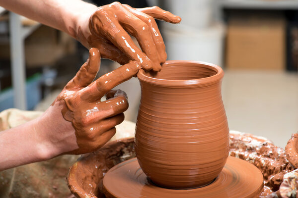 hands of a potter, creating an earthen jar