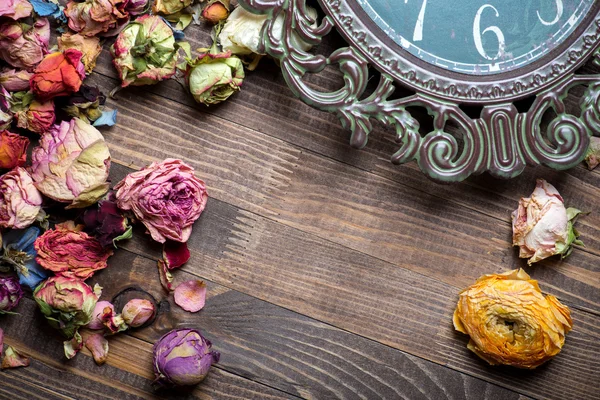 Abstract holiday frame with rose petals and dried flowers on old wooden plates. — Stock Photo, Image