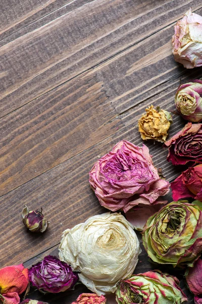 Abstract holiday frame with rose petals and dried flowers on wooden plates. — Stock Photo, Image