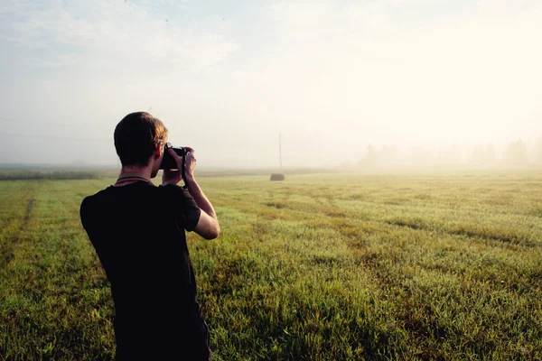 Fotógrafo no nevoeiro tirando uma foto da paisagem — Fotografia de Stock