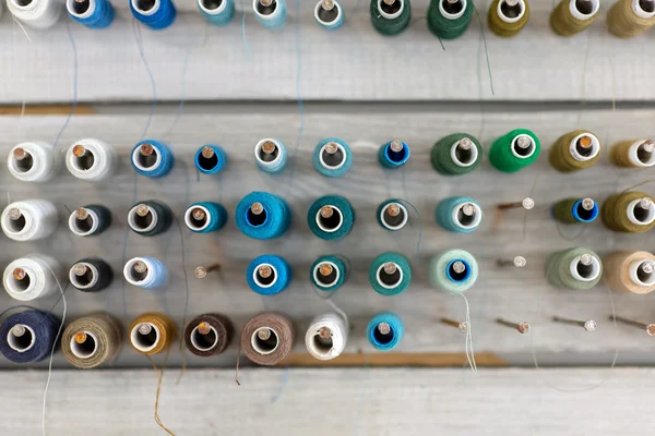 Klossen met kleurrijke draden op oude houten tafel achtergrond, naaien achtergrond — Stockfoto