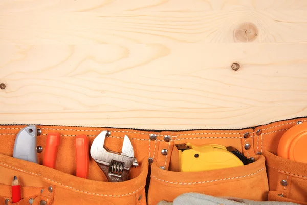 Süet kemer ahşap arka plan üzerinde çalışma araçlar kümesi ile