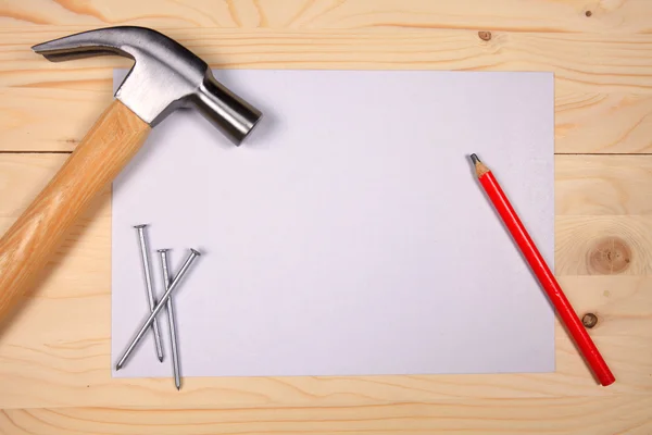 Hammer und Nägel auf Holzgrund mit Blatt Papier — Stockfoto