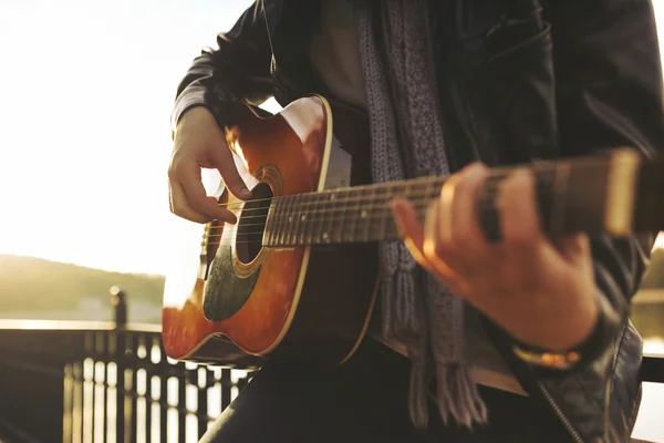 Молодий чоловік грає на гітарі біля озера — стокове фото