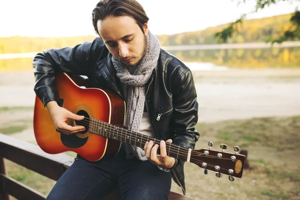 Young man playing on guitar at the lake — Stock Photo, Image