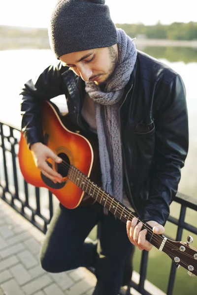 Young man playing on guitar at the lake — Stock Photo, Image