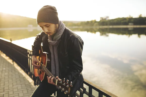 Young man playing on guitar at the lake — Stock Photo, Image