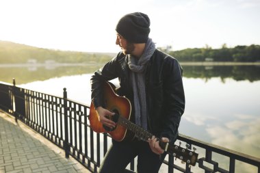 Genç adam gitar gölde oynamak