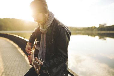 Genç adam gitar gölde oynamak