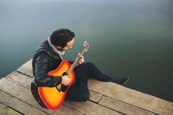 Young man playing on guitar at the lake — Stock Photo, Image