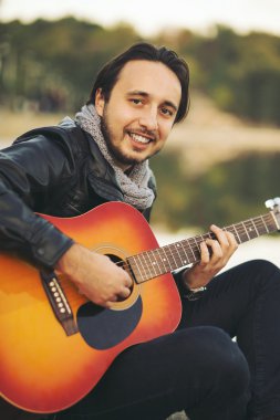 Genç adam gitar gölde oynamak