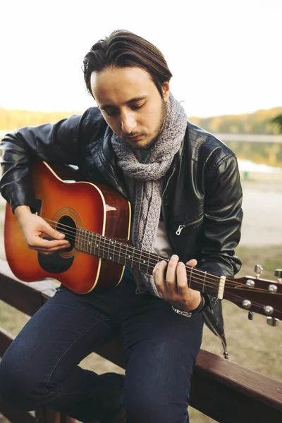 Young man playing on guitar at the lake — Stock Photo, Image