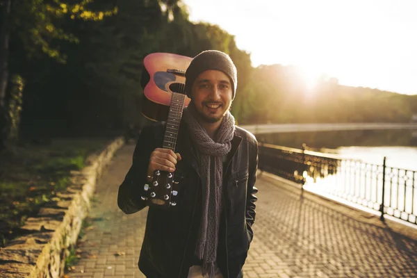Young man walks by the lake and holding guitar — Stock Photo, Image