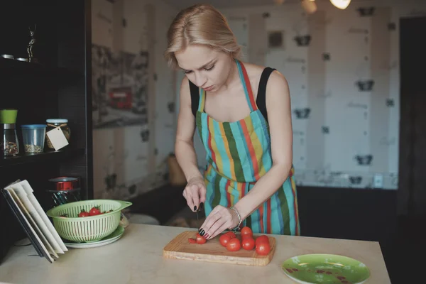 Молода жінка нарізає помідори — стокове фото