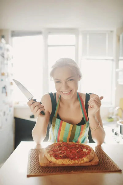 Jovem com uma faca cortar a pizza — Fotografia de Stock