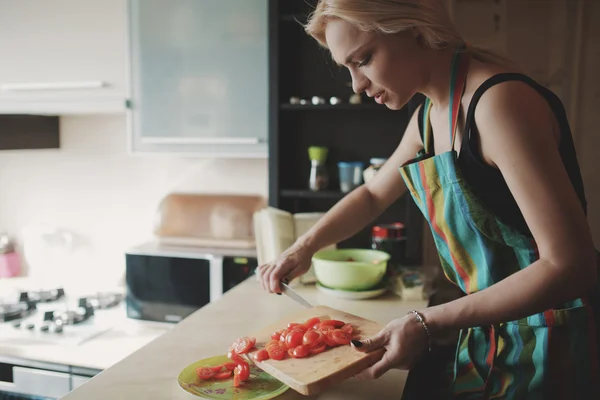 Молодая женщина режет помидоры — стоковое фото