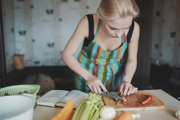 Молодая женщина режет овощи — стоковое фото