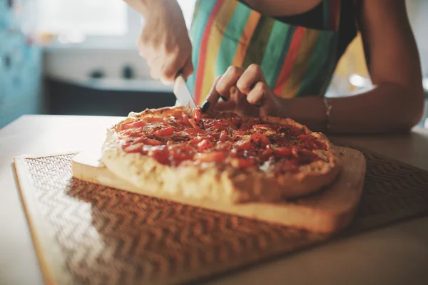 Mujer joven con un cuchillo cortar la pizza — Foto de Stock