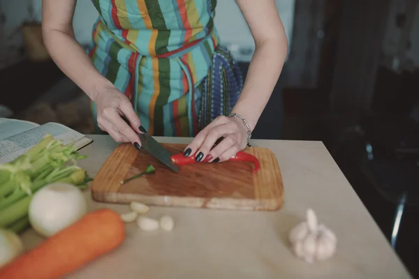 Молодая женщина режет овощи — стоковое фото