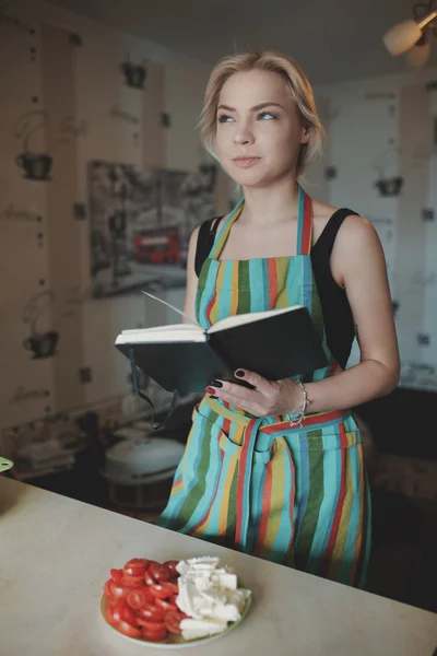 Молодая женщина смотрит вверх в книге рецептов — стоковое фото