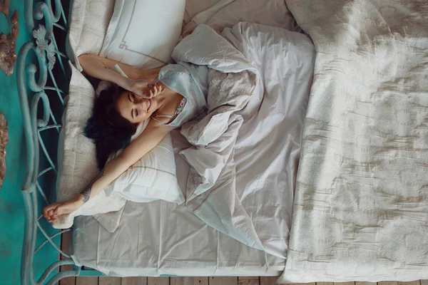 Mulher esticando na cama depois de acordar — Fotografia de Stock